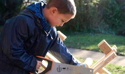 Child using a saw in forest school